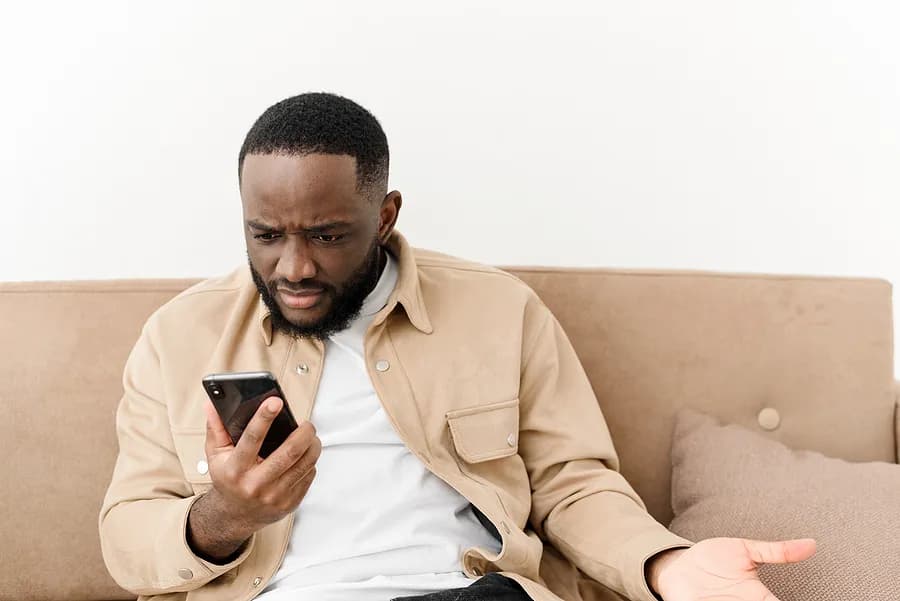 Mann auf der Couch mit dem Handy in der Hand