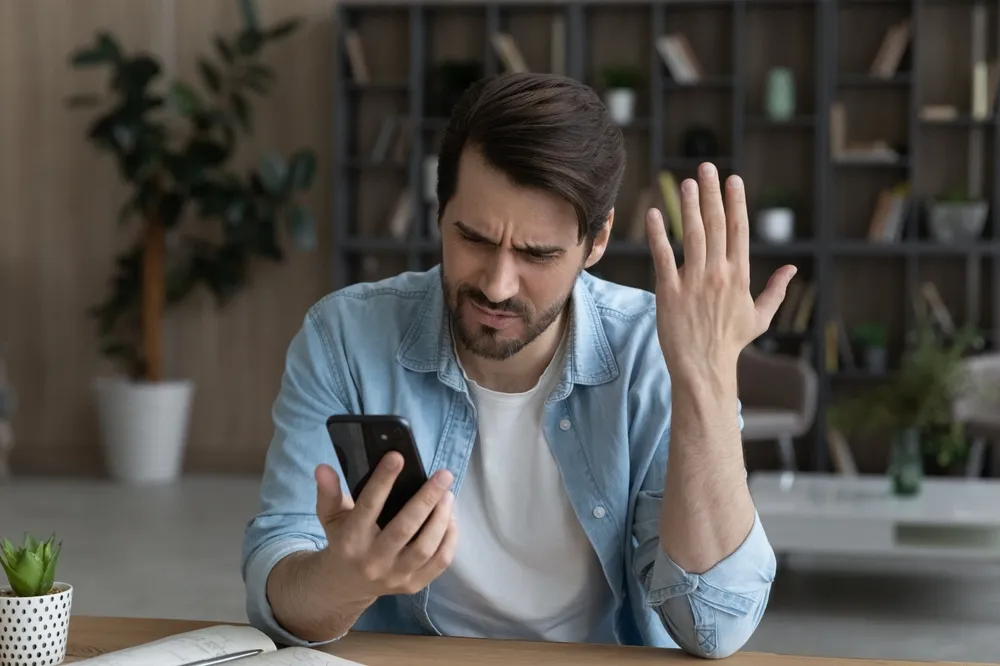 Mann, der durch sein Handy verwirrt ist