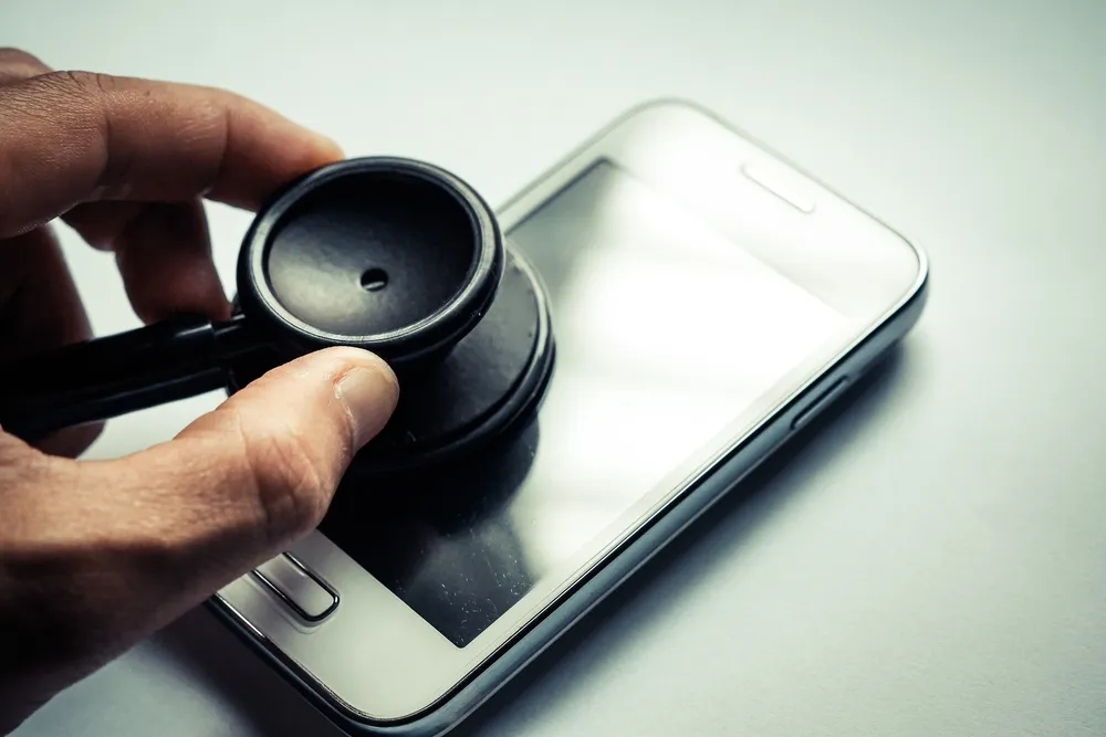 Mit einem Stethoskop an einem iPhone lauschen