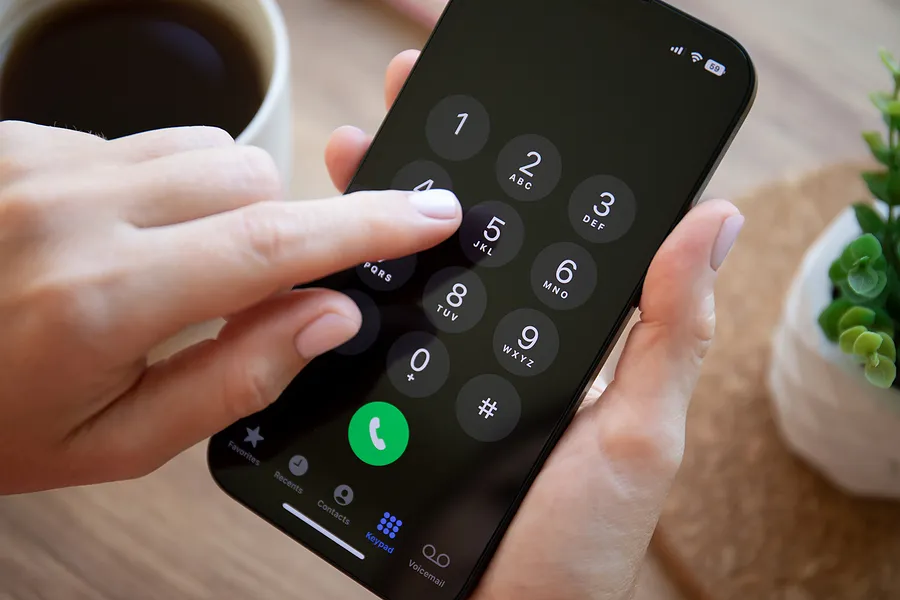 Finger, der Tasten auf einem iPhone 14 drückt