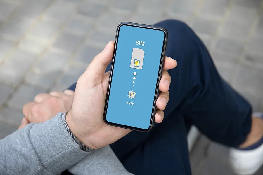 Eine Person, die mit gekreuzten Beinen dasitzt und ein Handy in der Hand hält