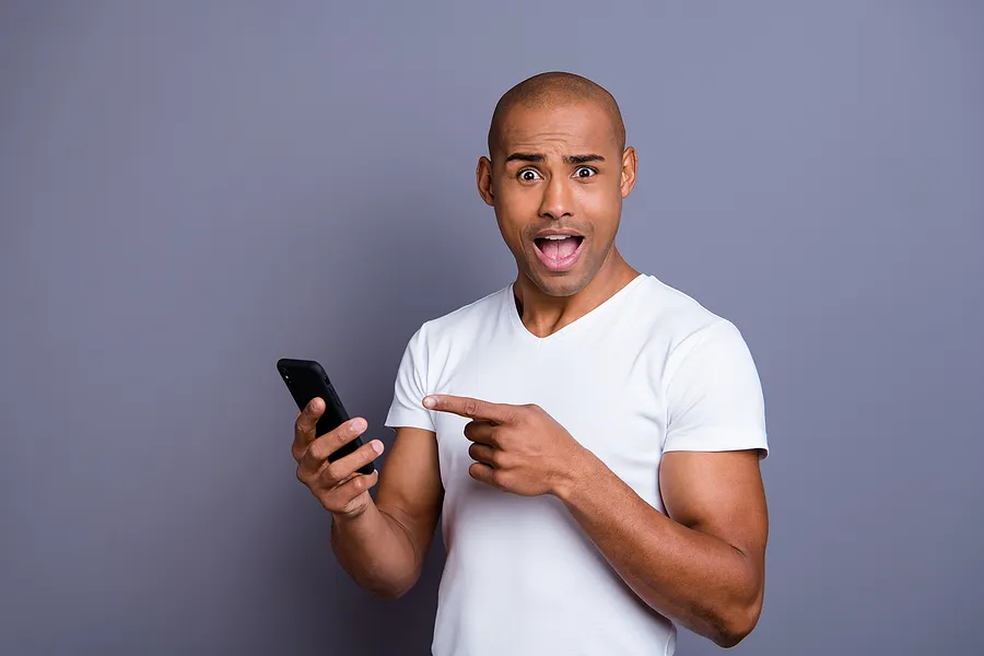 Ein Mann, der überrascht ein Handy in der Hand hält