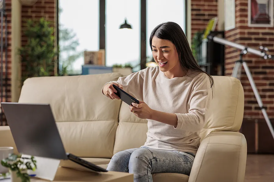 Eine Frau, die auf ihrem Handy Spiele spielt.