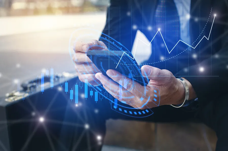 Geschäftsmann, der ein Smartphone nutzt, auf dessen Bildschirm digitale Finanzdiagramme eingeblendet sind