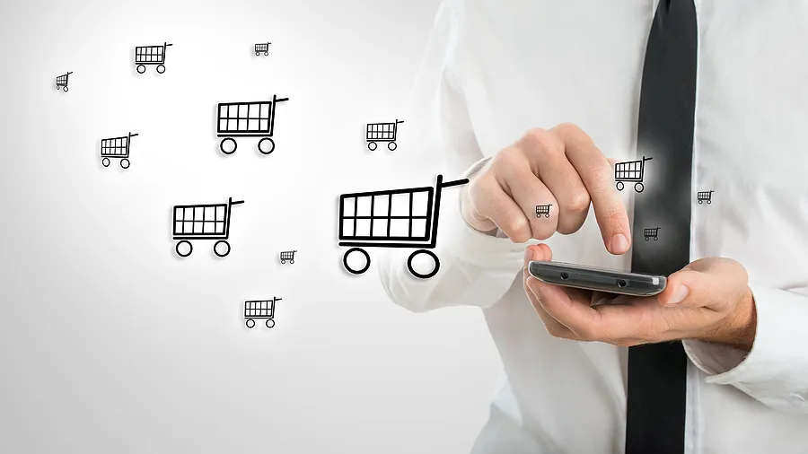 Geschäftsmann mit einem Smartphone, auf dem Einkaufswagen-Symbole zu sehen sind, die für mobilen E-Commerce und Online-Handykäufe stehen.