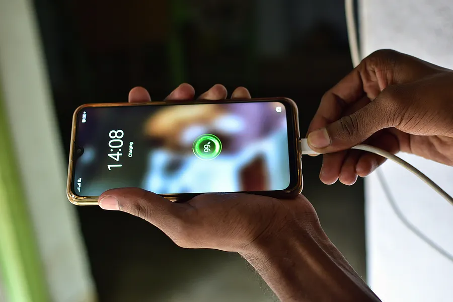 eine Person, die ein Smartphone an ein Ladegerät anschließt