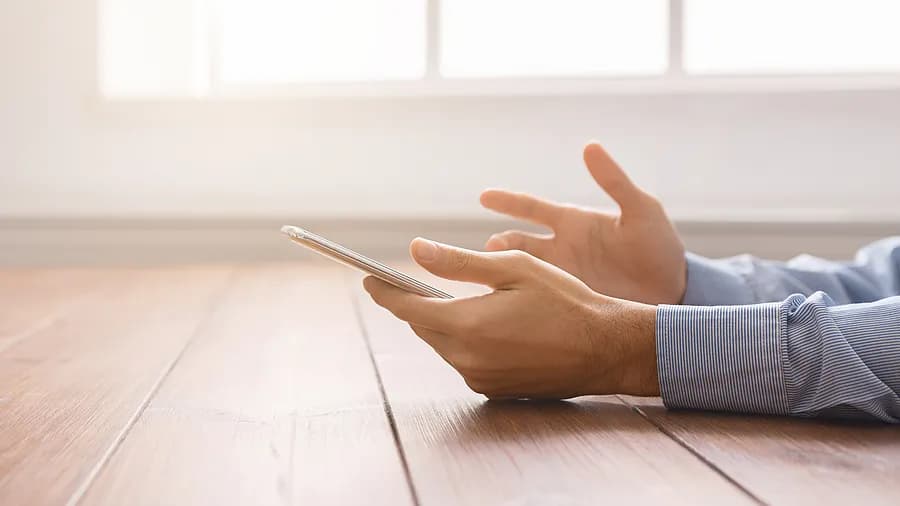 Eine Person, die ein iPhone in der Nähe eines Fensters hält, um zu veranschaulichen, wie man den iPhone-Passcode ohne Computer entsperrt.