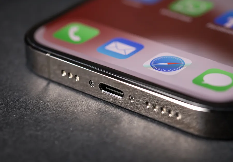 Nahaufnahme eines iPhone-Ladeanschlusses, auf dessen Bildschirm App-Symbole zu sehen sind; das Bild veranschaulicht Probleme beim Laden des iPhones.
